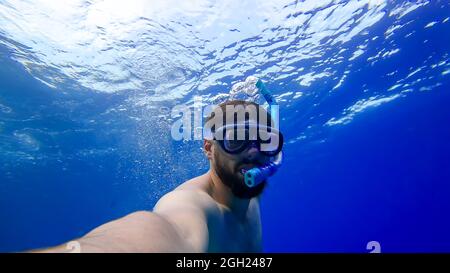 Ein Mann in Atemschläuchen und Masken stürzt auf den Grund des Roten Meeres ein bärtiger Mann ist mit Schnorcheln beschäftigt Stockfoto