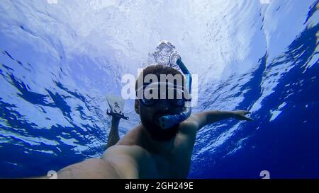 Ein Mann ist dabei, in einer Maske und einem Atemschlauch in die Tiefen des Roten Meeres zu schnorcheln Stockfoto