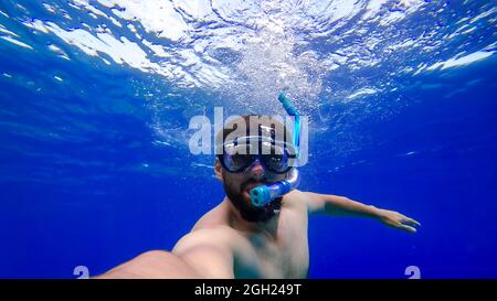 Ein Mann in Atemschläuchen und Masken stürzt auf den Grund des Roten Meeres ein bärtiger Mann ist mit Schnorcheln beschäftigt Stockfoto