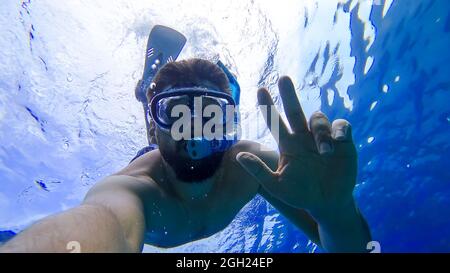 Ein Mann, der schnorchelt, ist nicht auf dem Roten Meer und zeigt mit seinen Händen verschiedene Gesten Stockfoto