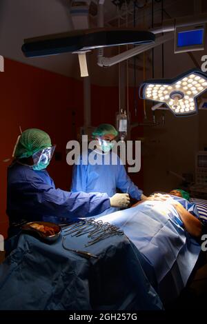 Chirurg Arzt Team arbeitet mit chirurgischen Geräten zusammen im Operationssaal, sie sind Heilpatienten, die sich auf das Bett legen. Stockfoto