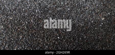 Textur von dunkelgrauem Sandpapier Asphalt Farbe Nahaufnahme. Stockfoto