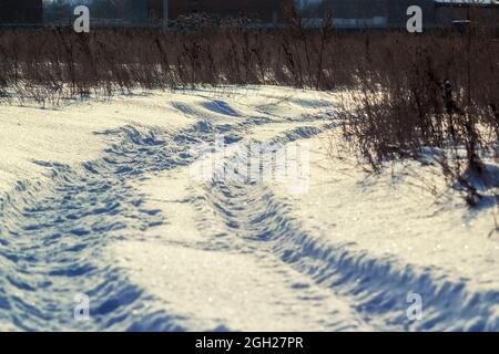 Schneebedeckte Straße auf dem Feld, die Markierungen der Räder. Stockfoto