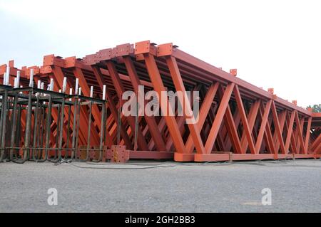 Die Stahlmetallkonstruktionen auf dem inneren Territorium des Industrieunternehmens. Lagerung von Traversen für die Installation des Dachs des Gebäudes. Stockfoto