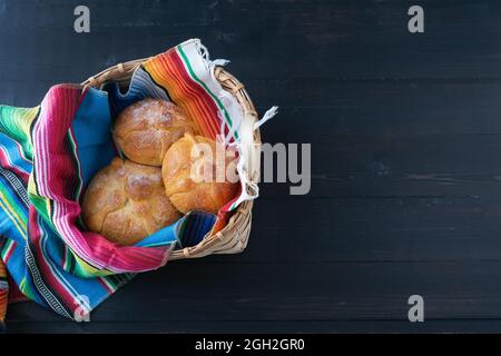 Brot der Toten in Holzkorb auf schwarzem Hintergrund. Tag der Toten. Mexikanischer Urlaub. Speicherplatz kopieren. Stockfoto