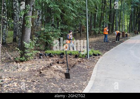 Nischni Nowgorod, Russland, Schweiz Park, Gagarin Avenue 113, 02.09.2021. Arbeiter Pflanzen im Park junge Bäume. Stockfoto