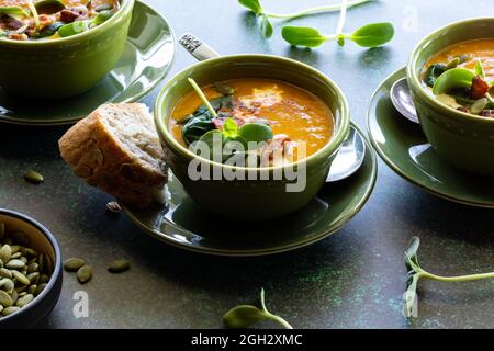 Nahaufnahme einer Schüssel mit Butternusskürzersuppe, serviert mit knusprigem Kürbiskernbrot. Stockfoto