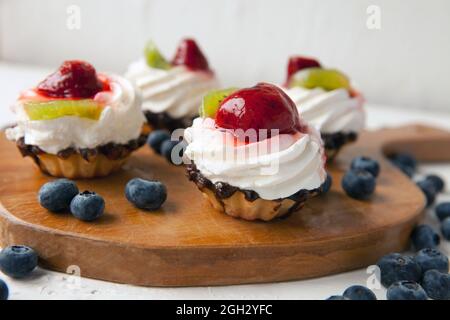 Cupcakes mit Quark auf Vintage-Tablett-leckerer Muffin mit Erdbeere und Kiwi auf Holzplatte Stockfoto