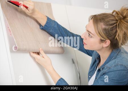 Frau klebend Furnier auf Schrank Stockfoto