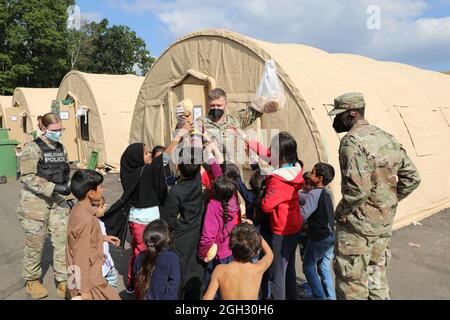 Soldaten der US-Armee der 18. Militärpolizeibrigade und der 16. Nachhaltigkeitsbrigade geben Kindern Brot zur Unterstützung der Operation Allies Refuge am 02. September 2021 auf der Ramstein Air Base, Deutschland. Soldaten des 21. Kommandos für Theaternachhaltigung haben bei der Bereitstellung von Sicherheit, Nahrung, Unterkünften und anderen grundlegenden Notwendigkeiten und der Säuberung im Transitzentrum auf RAB geholfen - alles Teil der Vorbereitung von Reisenden aus Afghanistan auf die Weiterreise zu ihrem endgültigen Bestimmungsort. (USA Armee-Foto von SPC. Katelyn Myers) Stockfoto