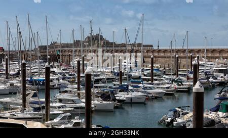 ST HELIER, JERSEY, KANALINSELN - 08. AUGUST 2021: Blick auf Elizabeth Castle im Hafen von St. Helier über Masten von Booten Stockfoto