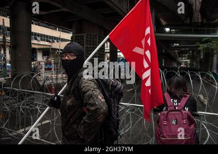 Bangkok, Thailand. September 2021. Während der Demonstration steht ein prodemokratischer Protestler mit einer Flagge vor dem Stacheldrahtzaun. Prodemokratische Demonstranten versammelten sich an der Kreuzung Ploenchit, bevor sie die Straße von Sukhumvit entlang marschierten und den Rücktritt von Prayut Chan-O-Cha, Thailands Premierminister, forderten, weil die Regierung die COVID-19-Coronavirus-Krise und die Reform der Monarchie nicht bewältigt hat. Kredit: SOPA Images Limited/Alamy Live Nachrichten Stockfoto