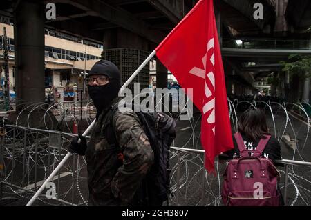 Bangkok, Thailand. September 2021. Während der Demonstration steht ein Demokratieprotesten mit einer Flagge vor dem Stacheldrahtzaun.Pro-Demokratie-Demonstranten versammelten sich an der Kreuzung Ploenchit, bevor sie die Straße von Sukhumvit entlang marschierten und den Rücktritt von Prayut Chan-O-Cha forderten, Thailands Premierminister über das Versäumnis der Regierung, die COVID-19-Coronavirus-Krise und die Reform der Monarchie zu bewältigen. Kredit: SOPA Images Limited/Alamy Live Nachrichten Stockfoto