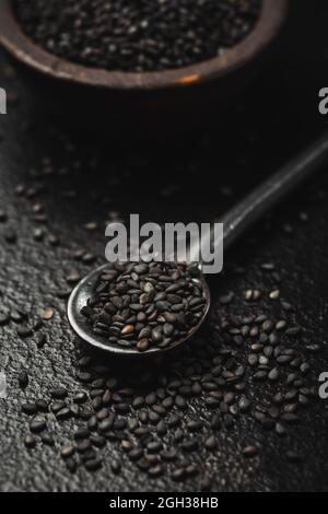Schwarze Sesamsamen in kleiner Schüssel auf schwarzem Hintergrund Stockfoto
