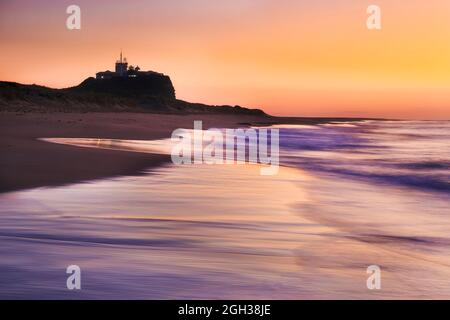 Nobbys Head Lighthouse am Newcastle Nobbyes Beach bei Sonnenaufgang - malerischer kolossischer Sonnenaufgang am Pazifik. Stockfoto