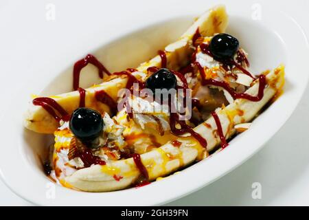 Banane mit Eis, Kirschen und Himbeer-Karamellsauce Stockfoto