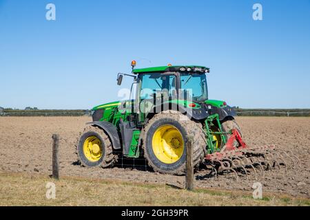 Canterbury, Neuseeland, September 3 2021: Ein John Deere Traktor mit Pflug sitzt auf einem ländlichen Feld, nachdem er ein Feld für die Aussaat vorbereitet hat Stockfoto