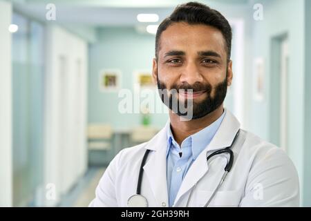 Lächelnder, indischer Arzt mit medizinischem Mantel und Blick auf die Kamera. Hochformat Stockfoto