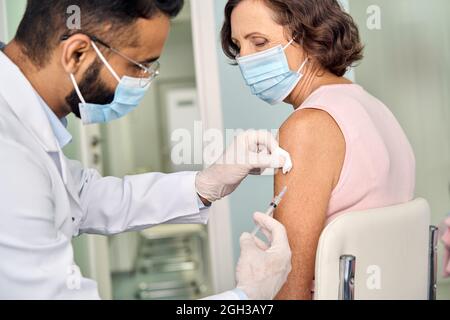 Ältere ältere Frau, die Gesichtsmaske trägt und Impfungen erhält. Stockfoto