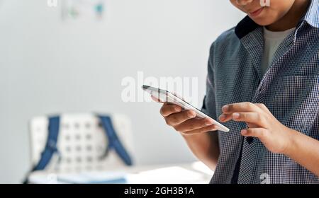 Asiatischer Junge Schüler mit Smartphone im Klassenzimmer, Nahaufnahme. Stockfoto