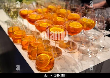 Viele Gläser mit einem alkoholischen Cocktail auf Basis von Aperol auf dem Buffettisch. Alkoholischer Cocktail Aperol Spritz. Alkoholcocktail an der Bar Stockfoto