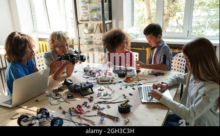 Verschiedene Schüler der Schule bauen mithilfe von Computern Roboterautos. Stockfoto