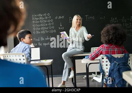 Lehrer, der Schüler in der Matheklasse mit einem digitalen Tablet im Klassenzimmer unterrichtet. Stockfoto