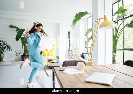 Erfolgreiche Latina Geschäftsfrau tanzt im Bürokleid und feiert glücklich bei der Arbeit. Stockfoto