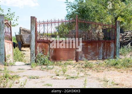 Alte, klapprige Tore. Altes rostiges Tor in einem verlassenen Haus. Kaputtes Tor. Stockfoto