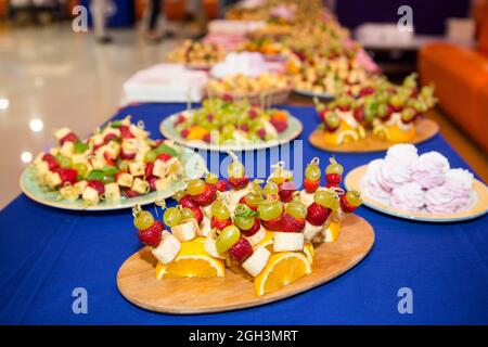 Süßer Buffettisch. Wunderschön dekorierter Catering-Banketttisch mit Burgern, Profiteroles, Salaten und kalten Snacks. Verschiedene leckere Snacks Stockfoto