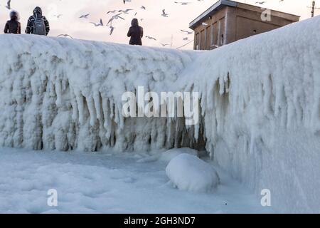 Vereisung. Die Winterkatastrophe, die die Seepromenade nach dem Wintersturm überzieht. Uferung des Ozeans während der Vereisung Stockfoto