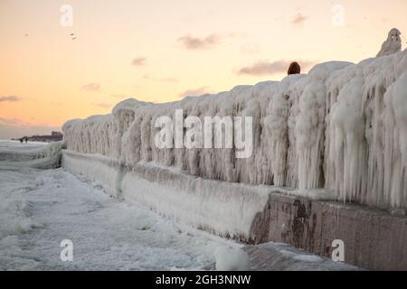 Vereisung. Die Winterkatastrophe, die die Seepromenade nach dem Wintersturm überzieht. Uferung des Ozeans während der Vereisung Stockfoto