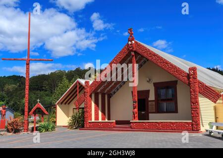 Whakarewarewa Maori Village, Rotorua, Neuseeland. Die Wharenui (Versammlungshaus) und Pou haki (Fahnenmast), beide mit traditionellen Schnitzereien bedeckt Stockfoto