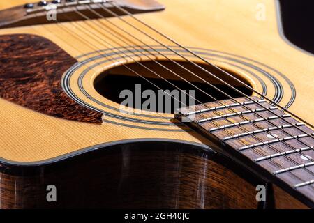 Teil einer akustischen Gitarre, Gitarre Griffbrett mit Saiten auf schwarzem Hintergrund. Stockfoto