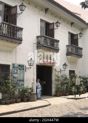 MANILA, PHILIPPINEN - 20. März 2008: Eine vertikale Aufnahme eines Restaurants und eines Soldaten in einer alten Straße in Manila auf den Philippinen Stockfoto
