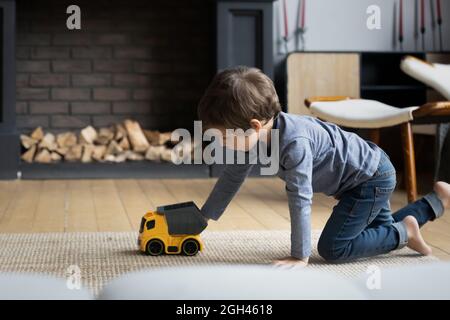 Fokussierter Junge, der zu Hause mit Spielzeug auf dem Heizboden spielt Stockfoto