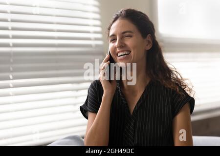 Fröhliche, aufgeregt lateinische Frau, die auf dem Handy spricht Stockfoto