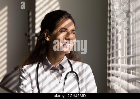 Glücklicher zufriedener Arzt, der aus dem Fenster schaute Stockfoto