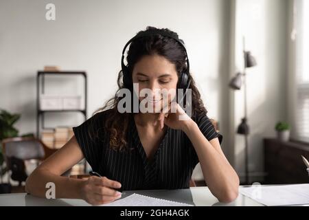 Fröhlicher Student mit Kopfhörern, der Webinar hört Stockfoto