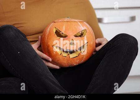 Crop-Ansicht von erwachsenen Mann auf dem Boden in der Küche mit geschnitzten halloween-Kürbis sitzen. Kürbis Jack-o-Laterne, drinnen. Trick or Trunk. Alles gute zum Halloween-Tag Stockfoto