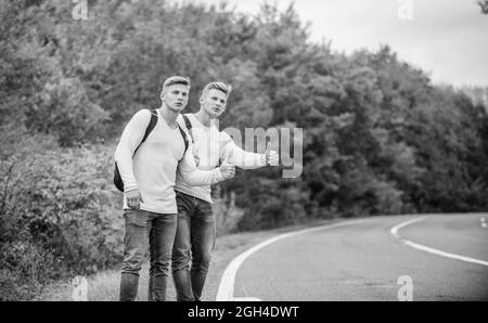 Reisende unterwegs. Freunde, die Wanderer auf Reisen halten. Anhalter-Geste. Beginnen Sie großes Abenteuer in Ihrem Leben mit dem Anhalten von Anhalter. Unternehmensfreunde Stockfoto