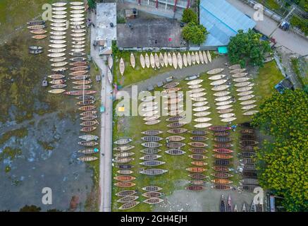 Manikganj, Dhaka, Bangladesch. September 2021. Als der Monsun über dem Distrikt Manikganj, Dhaka, Bangladesch aufragt, waren die Bootshersteller in diesem Distrikt sehr beschäftigt mit dem Bau von Booten, die in dieser Saison in ländlichen Gebieten als Schiffe eingesetzt werden. Die Nachfrage nach Dingi und Khosa Nauka (Kleinboot) ist hier nach regelmäßigen Bewegungen von Menschen in hochwassergefährdeten Gebieten gestiegen. Käufer von außerhalb des Bezirks, darunter Savar und Aminbazar von Dhaka, drängen Ghior Haat, Manikganj, um Boote zu kaufen. Auf diesem traditionellen Markt werden Hunderte von handgefertigten Holzbooten zum Verkauf auf dem Rasen bei A mar angelegt Stockfoto