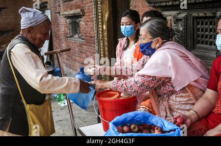 Kathmandu, Bagmati, Nepal. September 2021. Buddhistische Anhänger verteilen Opfergaben an einen älteren Mann während des Pancha Dan Festivals in Kathmandu, Nepal, 5. September 2021. Pancha Dan, das Fest der fünf Sommergeschenke, wird von den Buddhisten beobachtet, indem sie fünf Elemente wie Weizenkörner, Reiskörner, Salz, Geld und Obst verschenken. (Bild: © Sunil Sharma/ZUMA Press Wire) Stockfoto