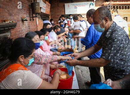 Kathmandu, Bagmati, Nepal. September 2021. Die Menschen erhalten während des Pancha Dan Festivals in Kathmandu, Nepal, 5. September 2021, Opfergaben, die von buddhistischen Anhängern verteilt werden. Pancha Dan, das Fest der fünf Sommergeschenke, wird von den Buddhisten beobachtet, indem sie fünf Elemente wie Weizenkörner, Reiskörner, Salz, Geld und Obst verschenken. (Bild: © Sunil Sharma/ZUMA Press Wire) Stockfoto