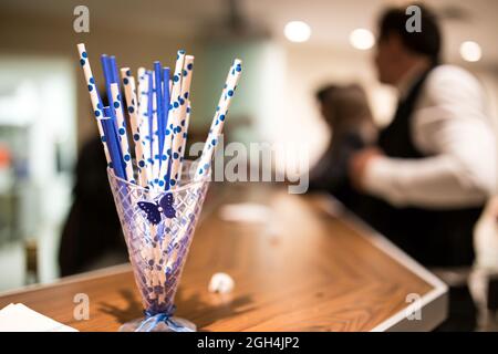 Eine selektive Fokusaufnahme von gepunkteten Cocktailhalmen aus Kunststoff in einem Glasglas in der Bar Stockfoto