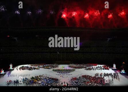Teams aus allen Ländern umgeben die Bühne, während das Feuerwerk während der Abschlusszeremonie der Paralympischen Spiele von Tokio 2020 im japanischen Olympiastadion explodiert. Bilddatum: Sonntag, 5. September 2021. Stockfoto
