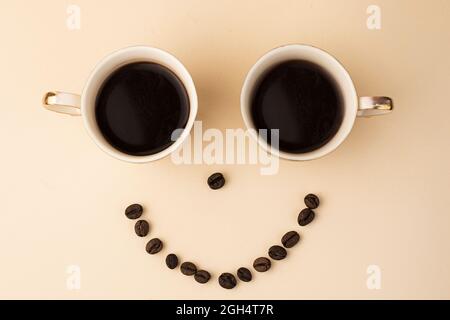 Tassen Kaffee und Kaffeebohnen auf hellem Hintergrund Stockfoto