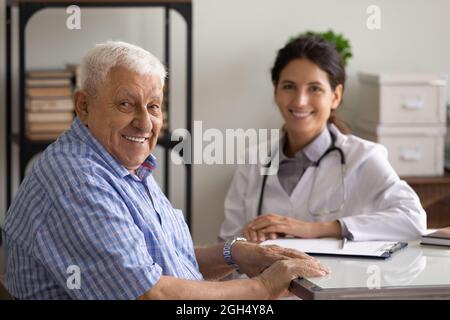 Glücklicher älterer Mann und junge Ärztin zum Termin Stockfoto