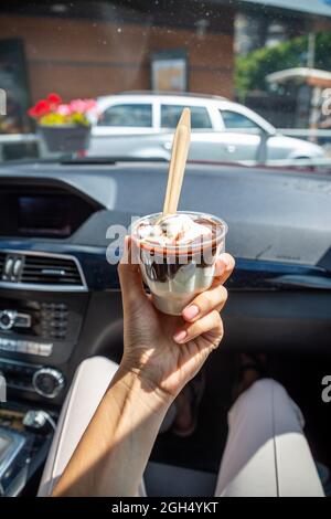 Frau, die das McDonalds McFlurry Ice Cream mit Schokolade in einem Auto nach der Durchfahrt hält. Drive-Thru-Konzept Stockfoto