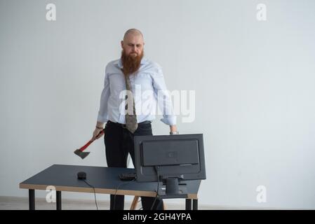 Gestresste verrückte Geschäftsmann zerschlagen seinen Computer im Büro mit Axt Problem Konzept. Der Mann hat Probleme bei der Arbeit und Frustration. Stockfoto